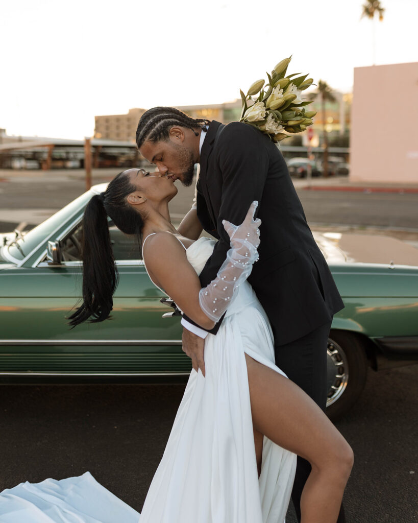 Sexy modern bride and groom kissing with pearl studded gloves and classic car
