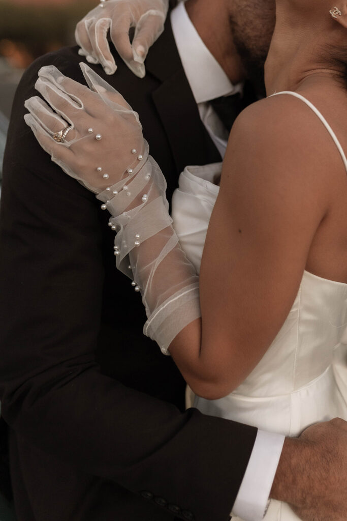 pearl studded gloves on an elegant bride and groom hugging close