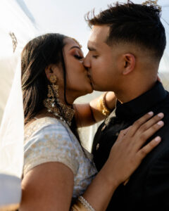 South Asian couple kissing in traditional wedding attire