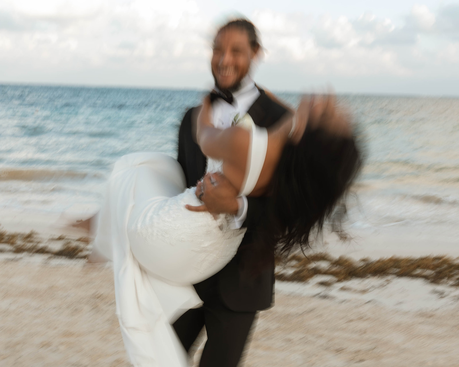 Groom carrying bride on the beach in Cancun, Mexico