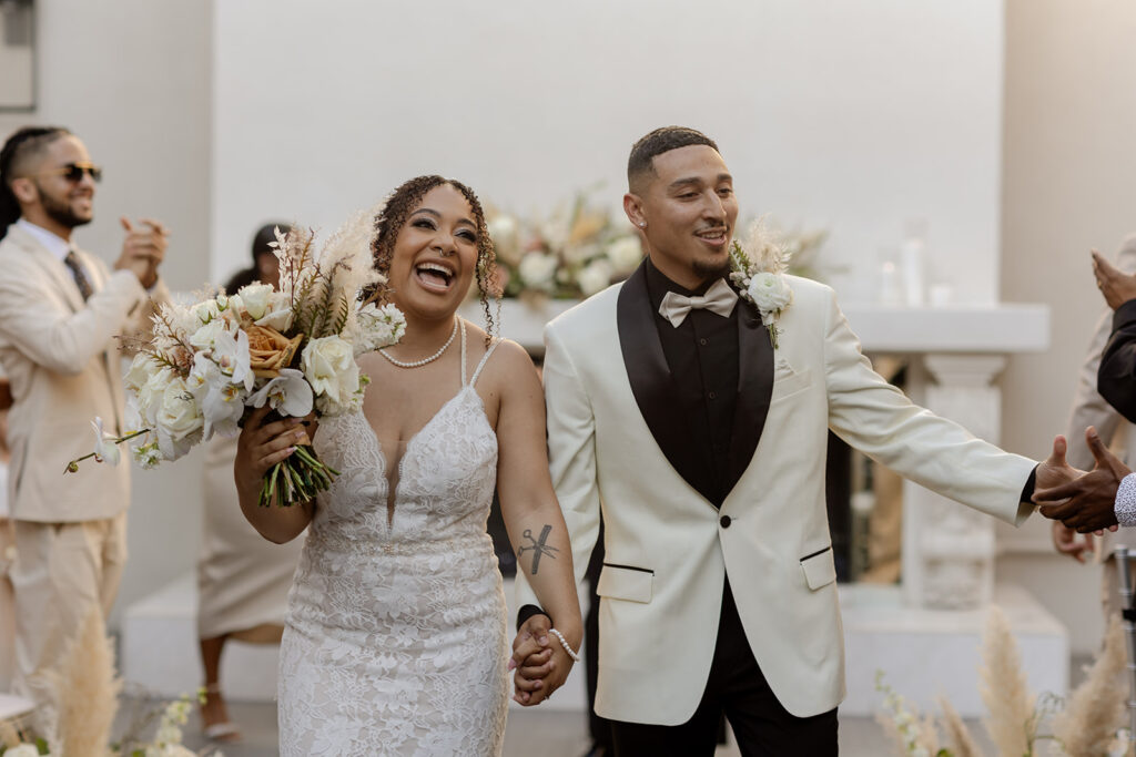 Gorgeous Black couple exits their wedding ceremony with big smiles